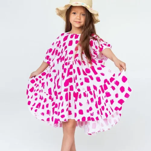 Witte zomerjurk voor kinderen met roze print, perfect voor op het strand.